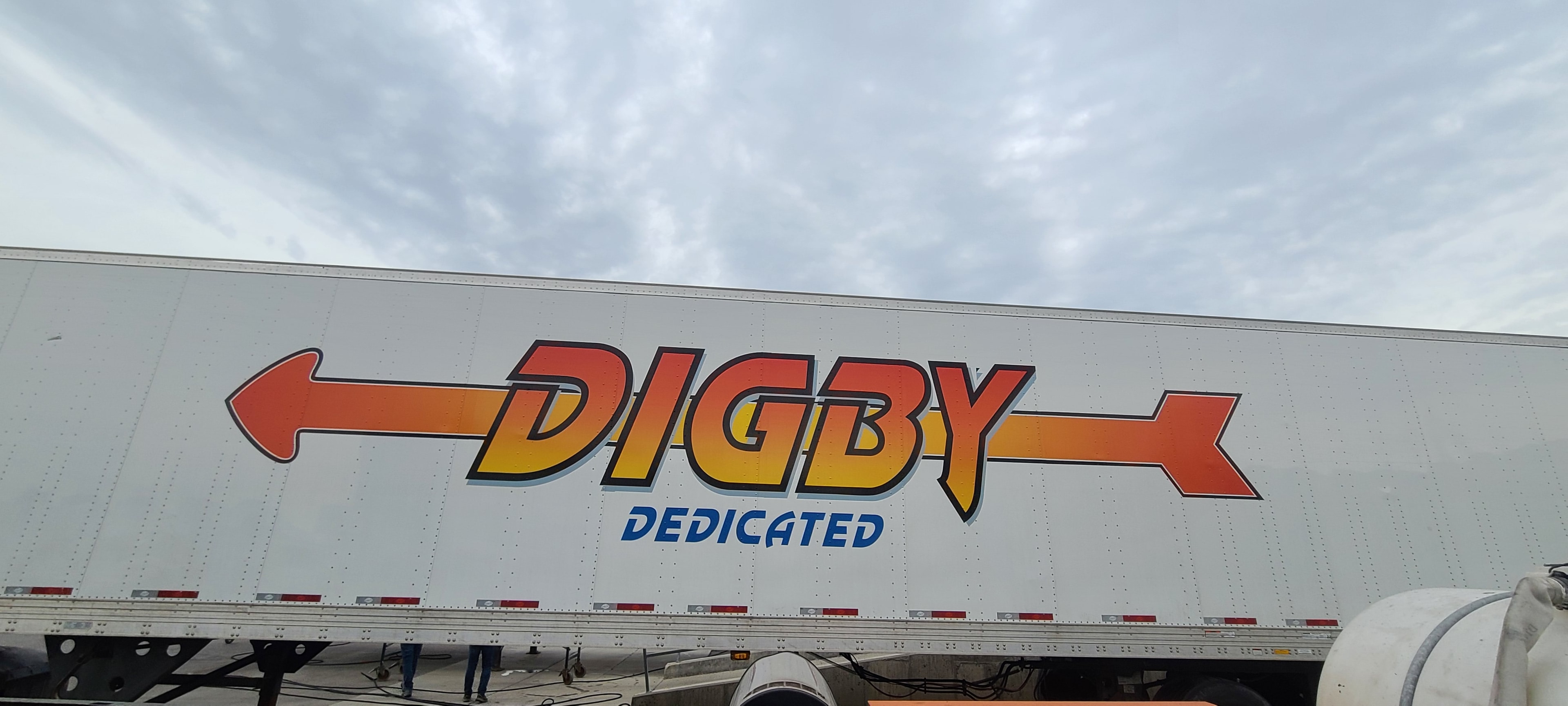 Close-up of Digby Dedicated arrow logo on 53ft trailer side panel before decal removal