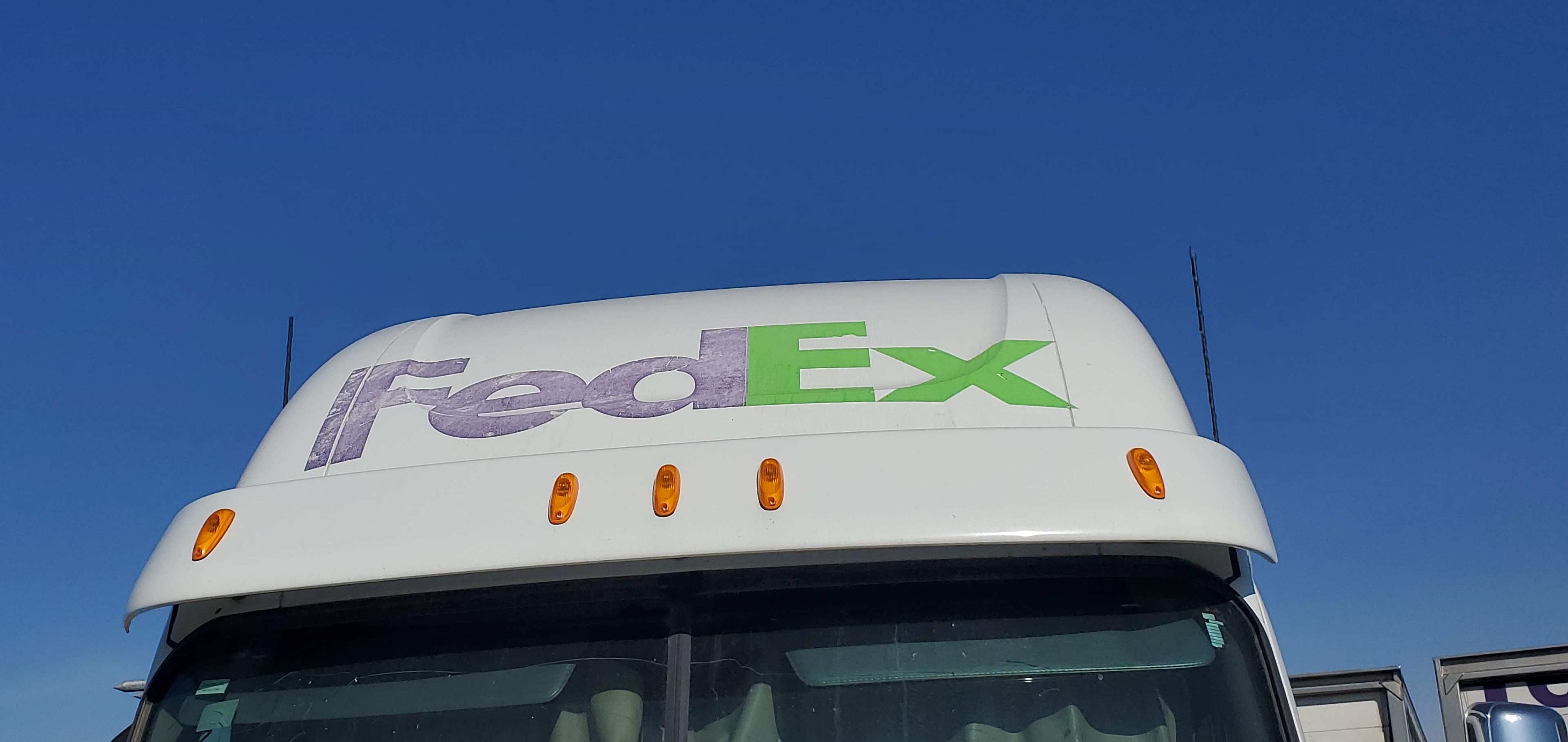 FedEx Ground semi truck roof fairing — faded FedEx Ground logo on cab visor before fleet rebranding