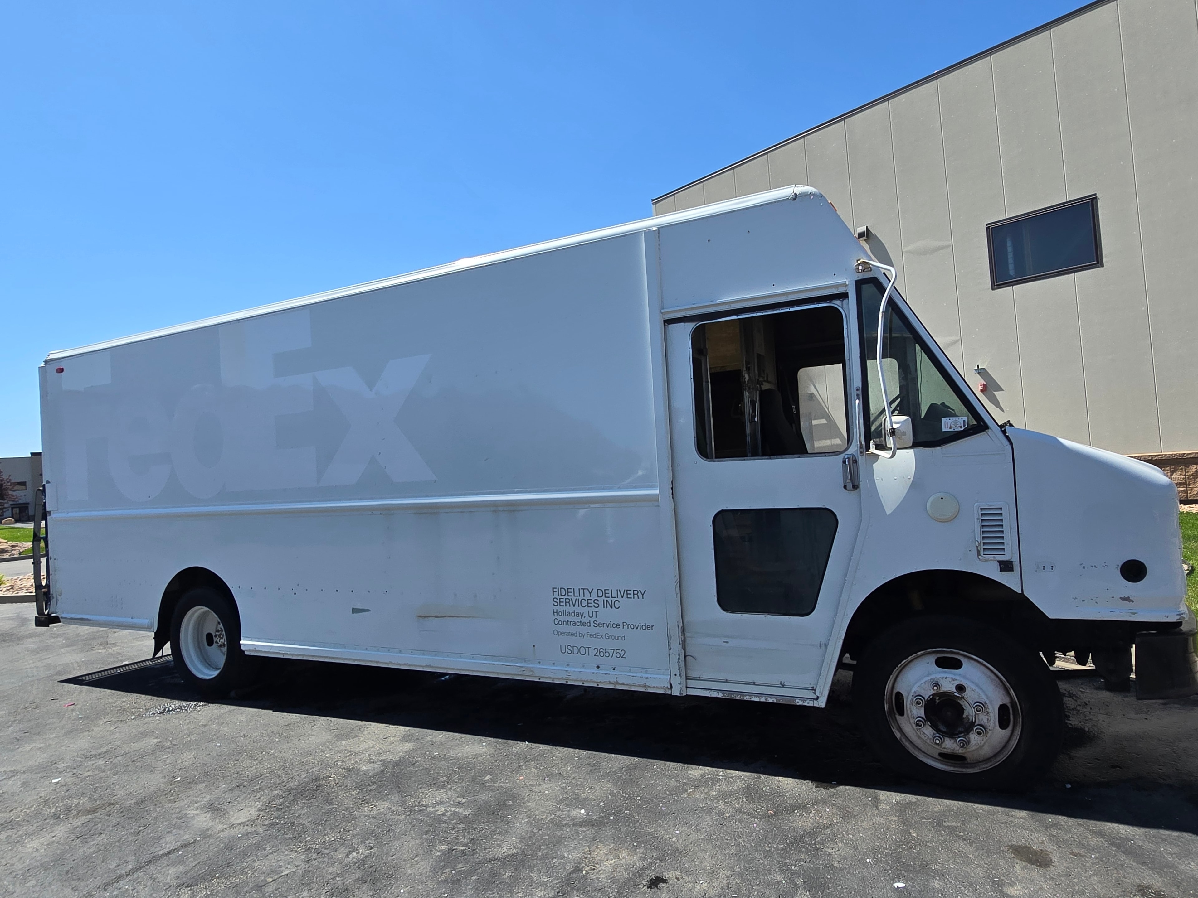 FedEx Ground step van side profile during de-identification — decals removed, adhesive ghosting outline visible on box body panel