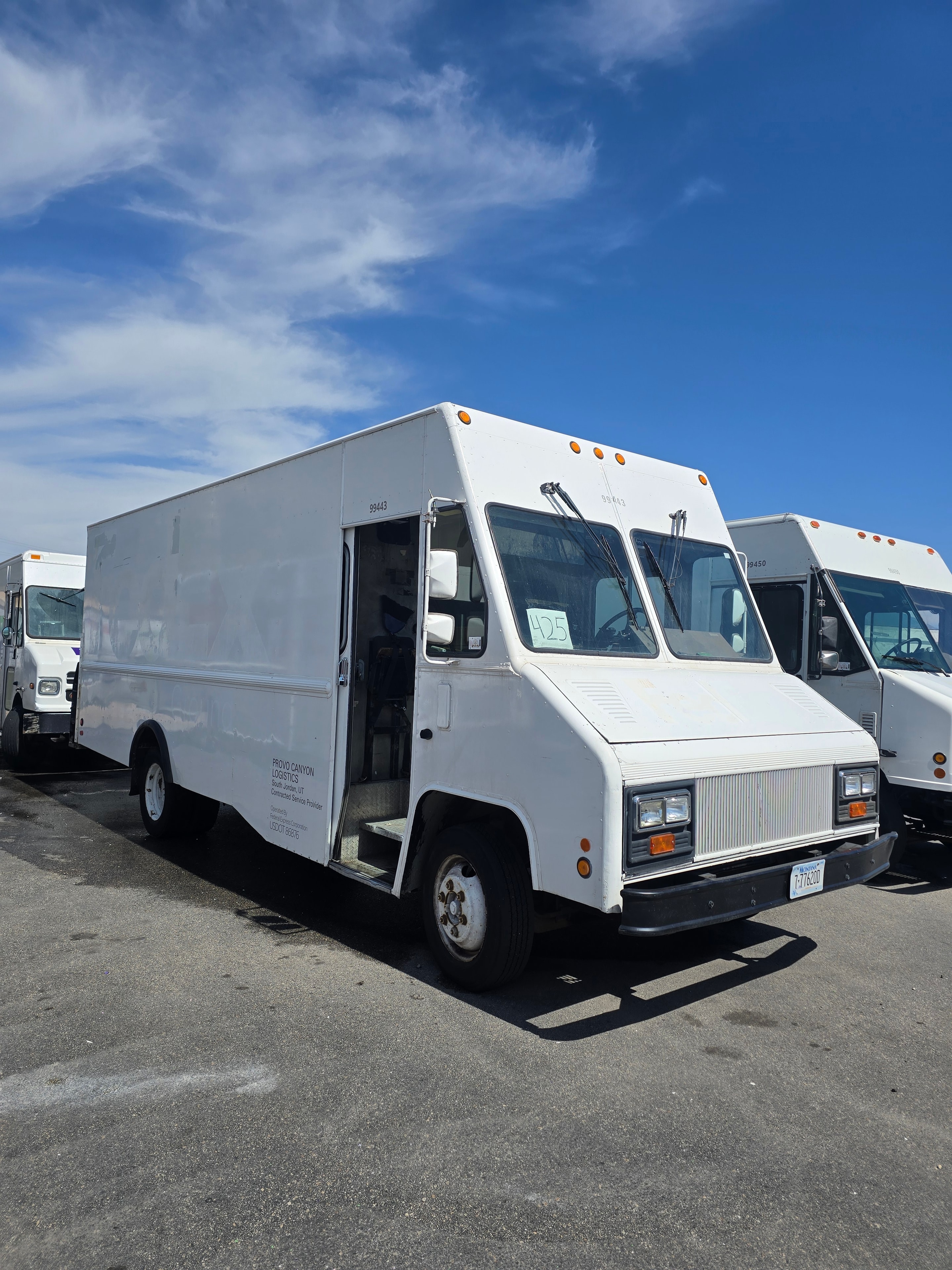 Multiple FedEx step vans lined up during de-identification — Provo Canyon Logistics fleet staged at Utah facility during rebranding project